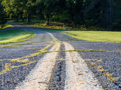 Closeup of worn road with double roadmarkings overgrown with grass. photo