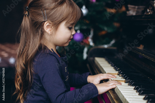 Portrait of a cute little girl playing an old piano on New Year's Eve