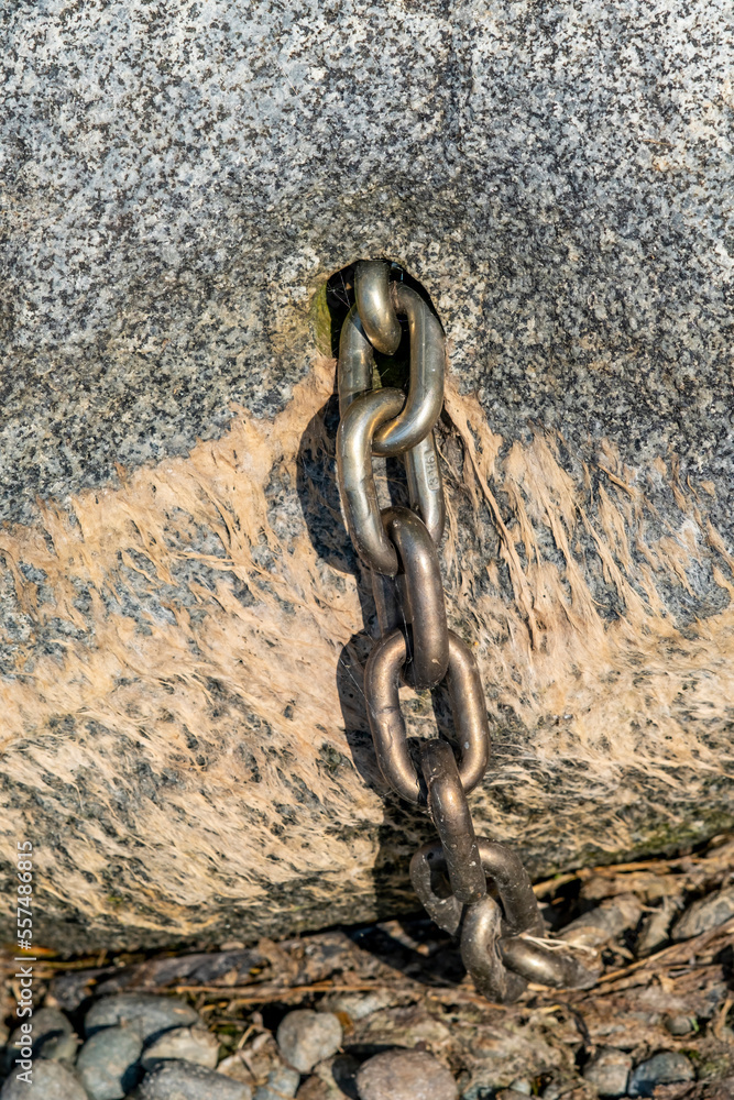 Chain emerging from boulder on beach Chain emerging from boulder on beach