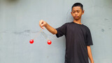 Kid holding lato-Lato. A traditional toy consisting of two heavy pendulums made of plastic and suspended by a string. Its traditional game can be found in Indonesia. These lato-lato have been very ic