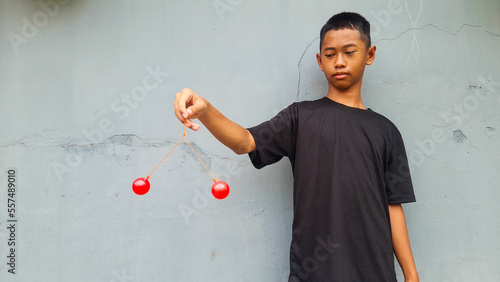 Kid holding lato-Lato. A traditional toy consisting of two heavy pendulums made of plastic and suspended by a string. Its  traditional game can be found in Indonesia. These lato-lato have been very ic photo