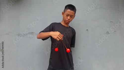 Kid holding lato-Lato. A traditional toy consisting of two heavy pendulums made of plastic and suspended by a string. Its  traditional game can be found in Indonesia. These lato-lato have been very ic photo