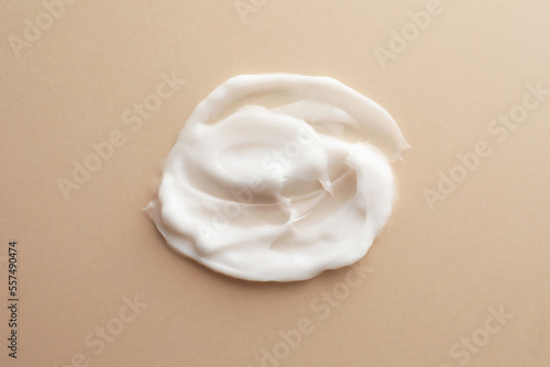 Sample facial cream on beige background, top view