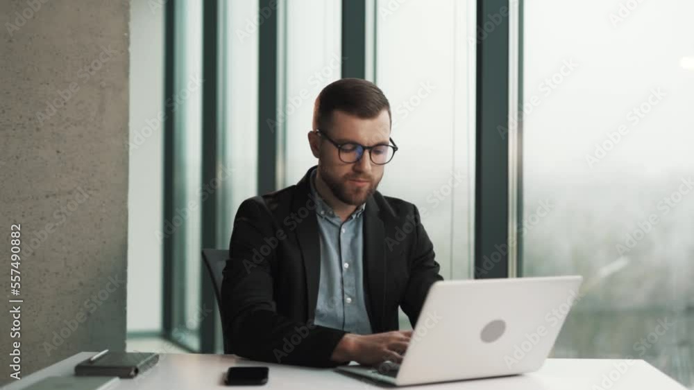 A pensive man in a business suit is concentrating on a laptop A pensive man in a business suit is concentrating on a laptop