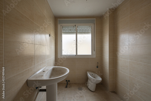 An empty unfinished bathroom with dirty tiles and uninstalled sanitary ware