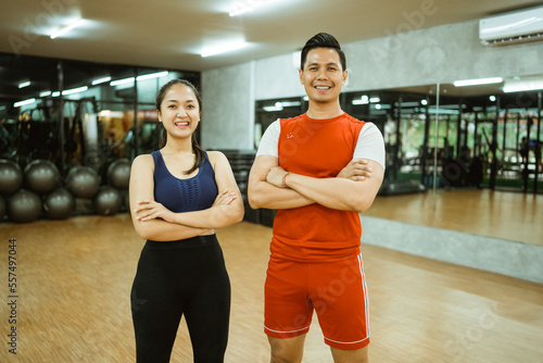 asian girl and man in sportswear smiling with crossed hands in gym