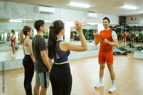 woman in sportswear asks by raising her hand during a briefing with an instructor before exercising