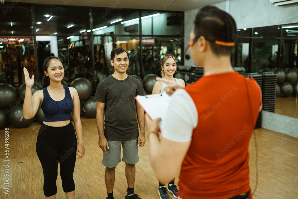 Asian male instructor leading three members for group briefing before working out at the fitness center Asian male instructor leading three members for group briefing before working out at the fitness center