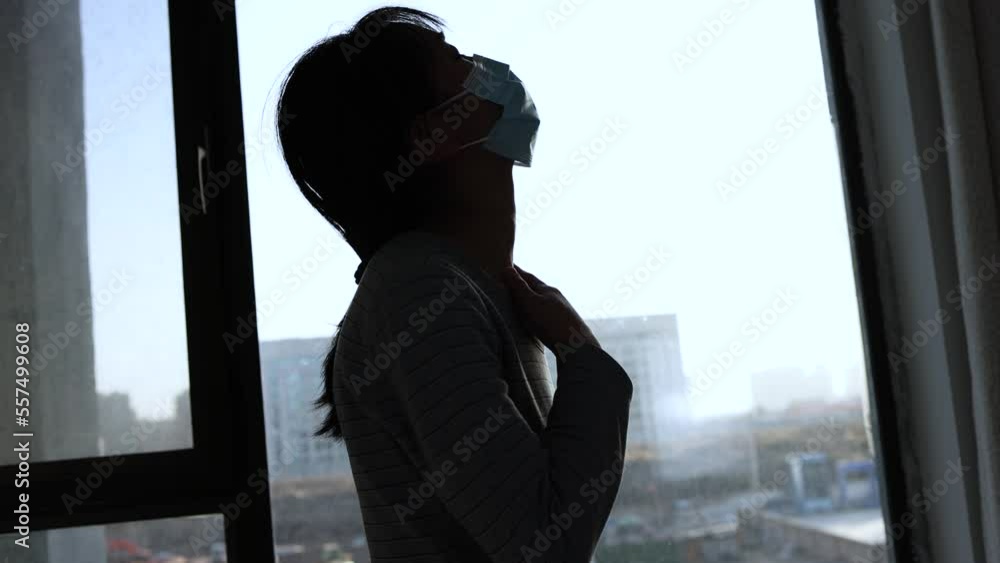 Silhouette of sick woman with cold cough and fever at window Silhouette of sick woman with cold cough and fever at window