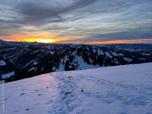 Magical sunset and shy sun behind winter clouds over the Obertoggenburg region and in the Swiss Prealps, Urnäsch (Urnaesch or Urnasch) - Canton of Appenzell Innerrhoden, Switzerland (Schweiz) photo