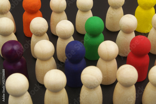 Colorful people figures in crowd of wooden people figures close up. Talent search, uniqueness, individuality, and recruitment concept.