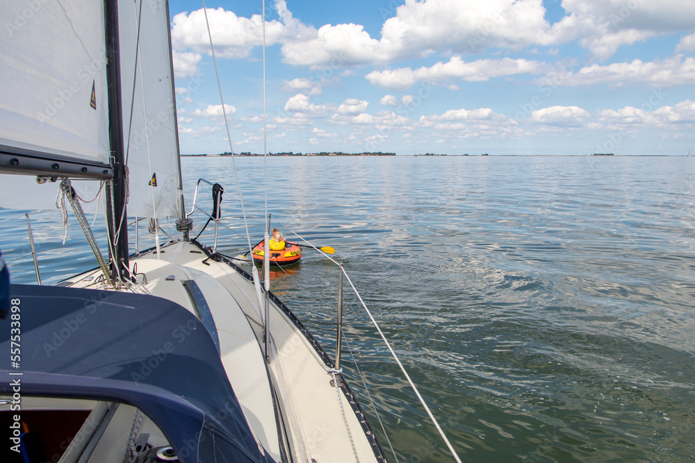 Small dinghy being towed behind a sailboat Small dinghy being towed behind a sailboat