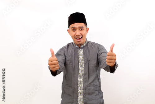 Happy asian muslim man standing while showing thumbs up. Isolated on white background