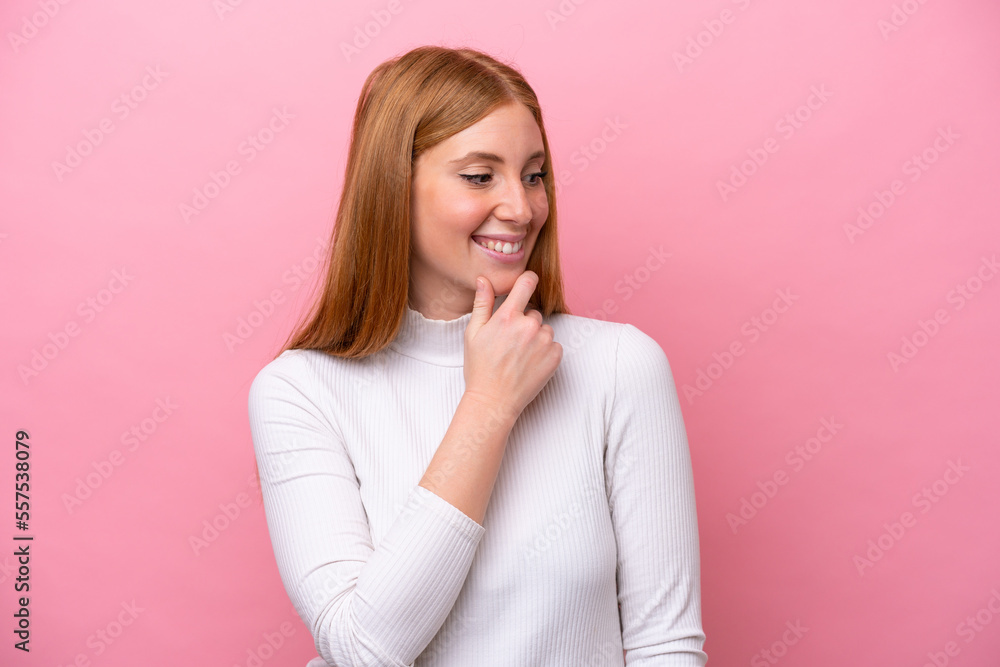 Young redhead woman isolated on pink background looking to the side and smiling Young redhead woman isolated on pink background looking to the side and smiling