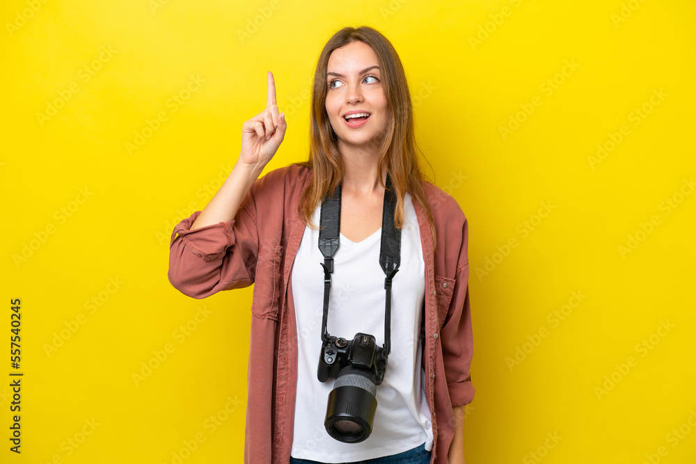 Young photographer caucasian woman isolated on yellow background intending to realizes the solution while lifting a finger up Young photographer caucasian woman isolated on yellow background intending to realizes the solution while lifting a finger up