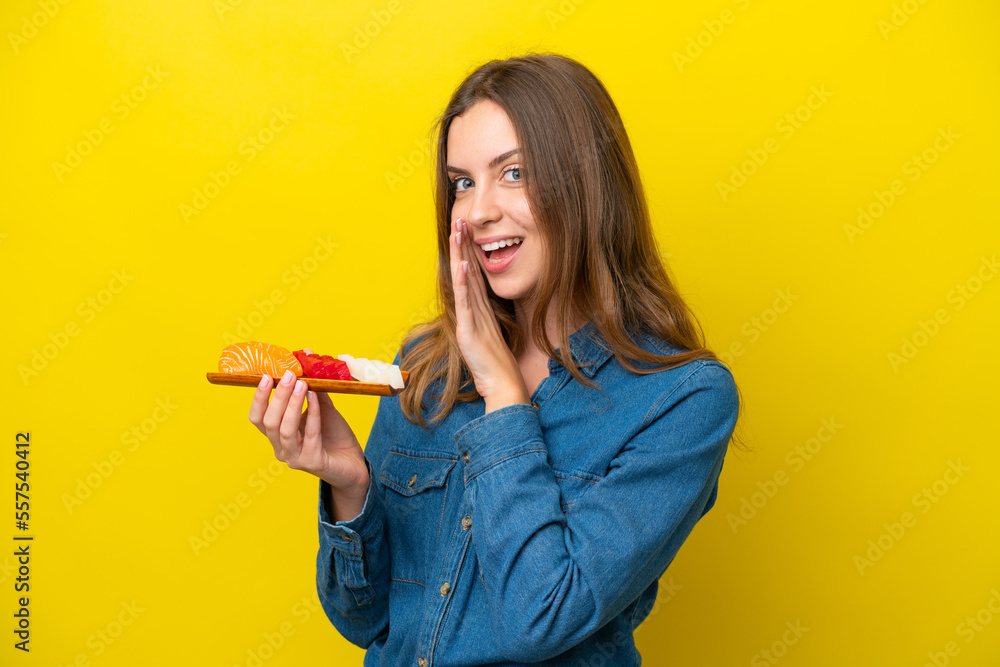 Young caucasian woman holding sashimi isolated on yellow background whispering something Young caucasian woman holding sashimi isolated on yellow background whispering something