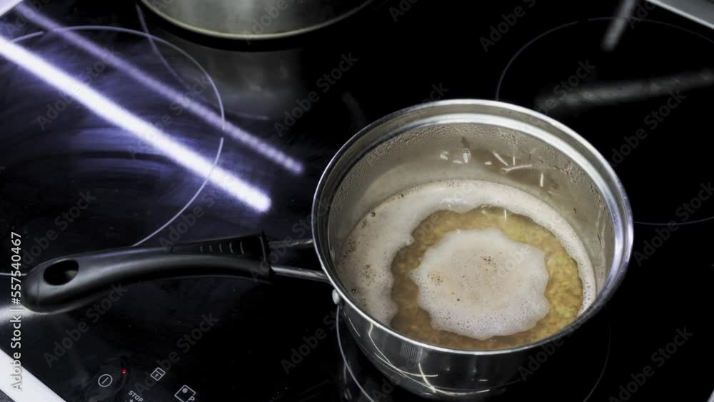 Buckwheat porridge is cooked in metal saucepan. Kitchen cooking food on induction cooker Buckwheat porridge is cooked in metal saucepan. Kitchen cooking food on induction cooker