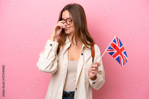 Young student caucasian woman holding an United Kingdom flag isolated on pink background laughing