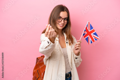 Young student caucasian woman holding an United Kingdom flag isolated on pink background making money gesture