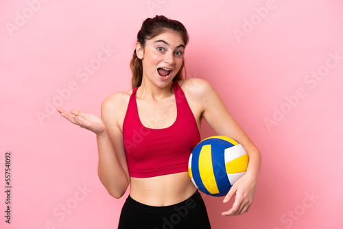 Young caucasian woman playing volleyball isolated on pink background with shocked facial expression