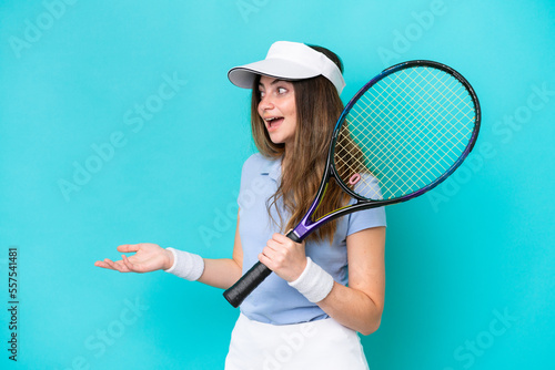 Young tennis player woman isolated on blue background with surprise expression while looking side