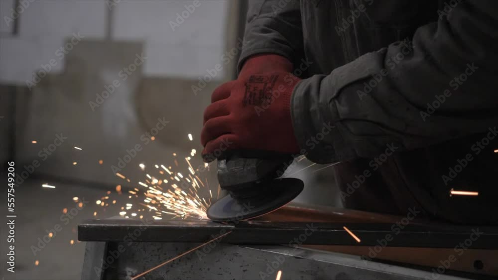 A worker grinds a metal part A worker grinds a metal part