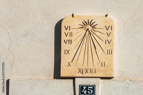 front view medium distance of a mechanical, sun dial, showing 10:02 AM, time, on external wall, in Sablet, Provence, France photo