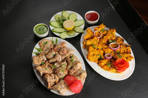 Chicken tikka black background served with green salad and sauces 