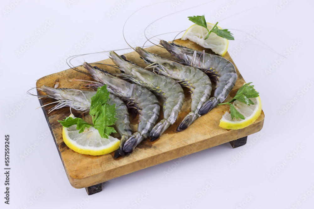 Fresh raw shrimps on wooden cutting board plate with lemon Fresh raw shrimps on wooden cutting board plate with lemon