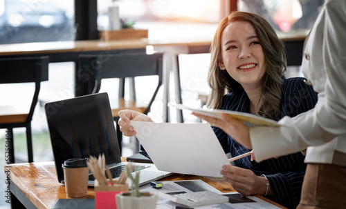 Two females in a suits, doing paper work.