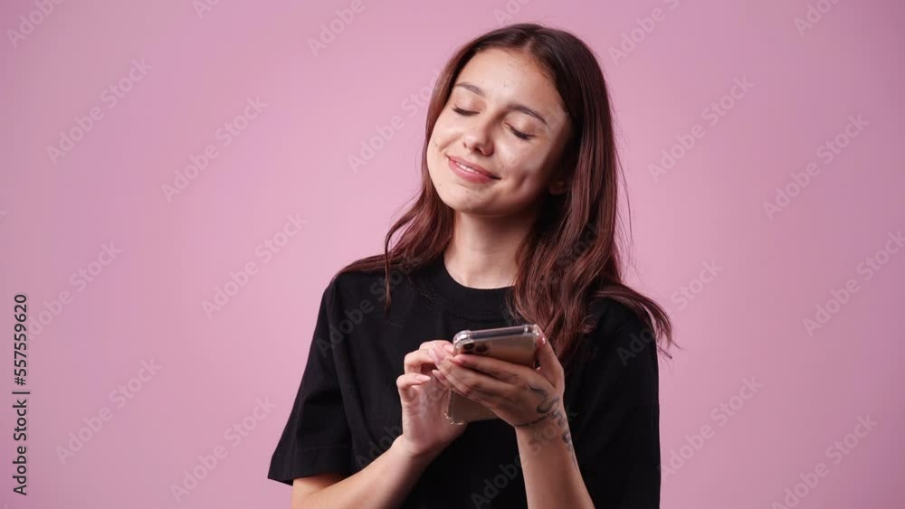 4k slow motion video of one girl using her phone over pink background. 4k slow motion video of one girl using her phone over pink background.