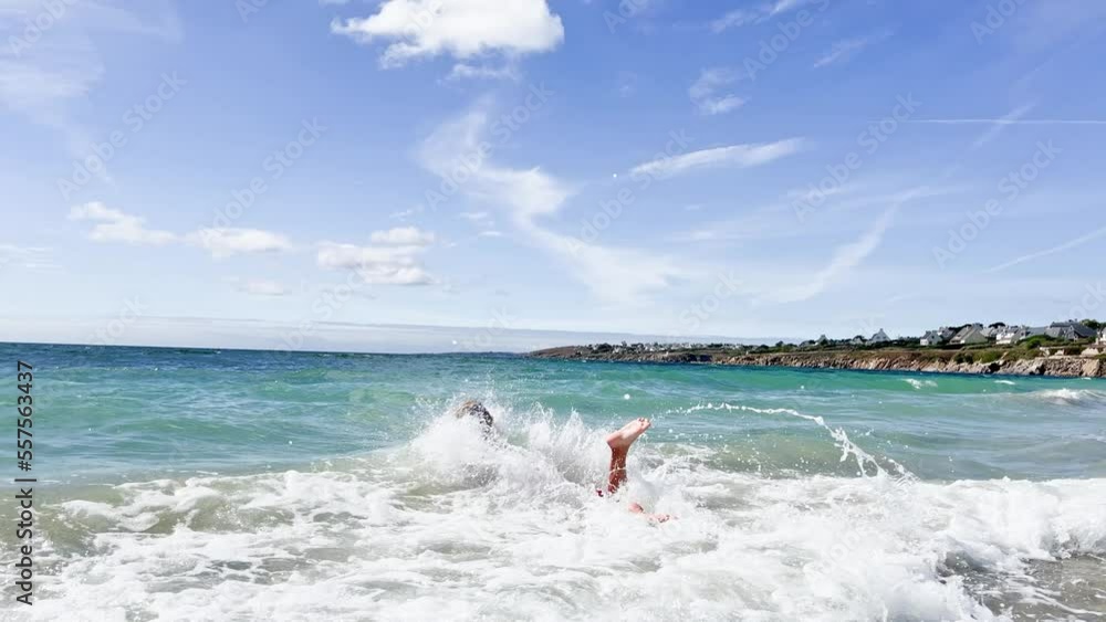 Handsome boy run and jump into ocean wave on the sand beach Handsome boy run and jump into ocean wave on the sand beach