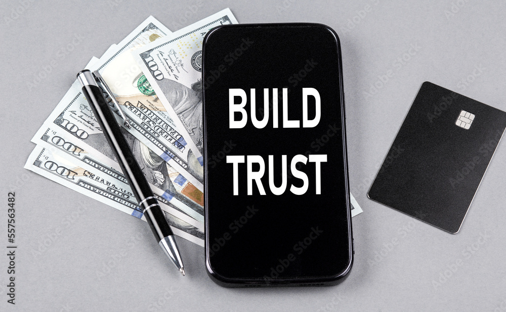 Credit card and text BUILD TRUST on smartphone with dollars and pen. Business concept Credit card and text BUILD TRUST on smartphone with dollars and pen. Business concept