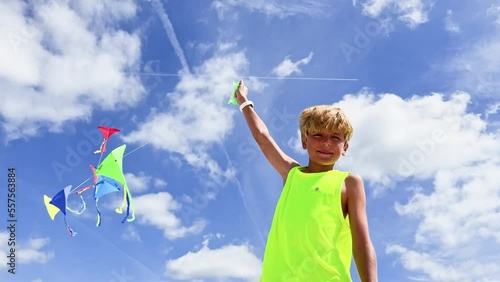 Low angle portrait of a boy with colorful kites set over sky