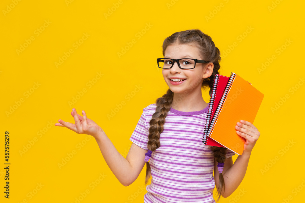 A teenage girl with colorful notebooks in her hands and glasses. A little girl is getting ready for school. Additional courses for the child. A teenage girl with colorful notebooks in her hands and glasses. A little girl is getting ready for school. Additional courses for the child.