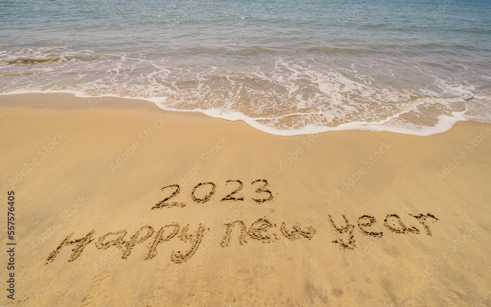 2023 happy new year handwritten in sand on a beautiful beach