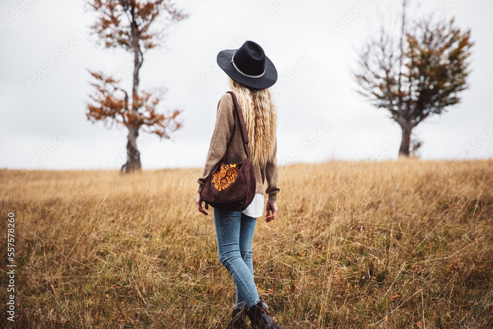 Φωτογραφία Fashionable young woman in a trendy suit in leather shoes and a handmade bag walking in the park