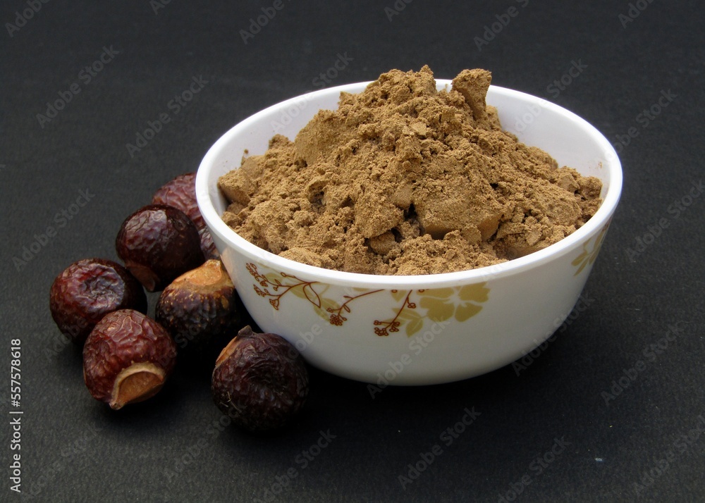 Sapindus mukorossi or Indian soapberry powder in a bowl on black background Sapindus mukorossi or Indian soapberry powder in a bowl on black background