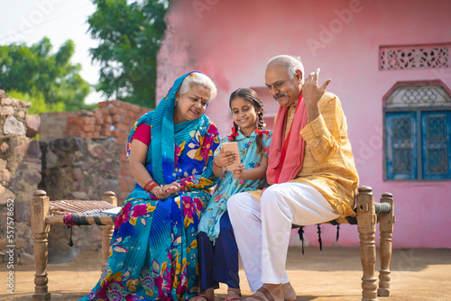 Indian little girl using smartphone with grandparents.