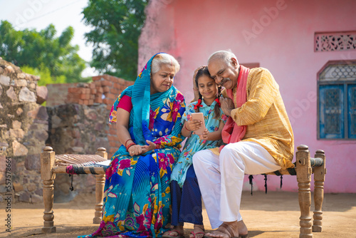 Indian little girl using smartphone with grandparents.