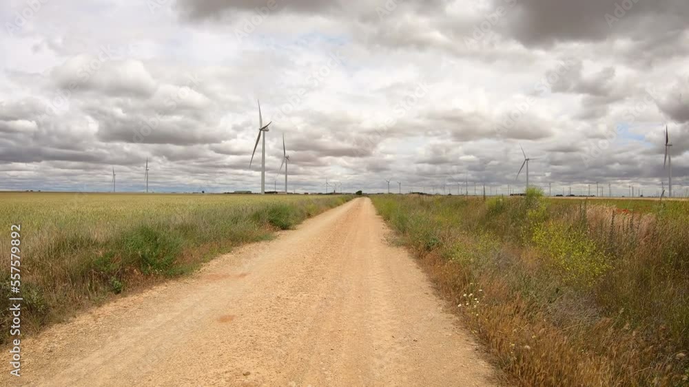 Camino de Madrid - a dirt road passing on a wind turbines farm next to Castromonte, province of Valladolid, Castile and Leon, Spain Camino de Madrid - a dirt road passing on a wind turbines farm next to Castromonte, province of Valladolid, Castile and Leon, Spain