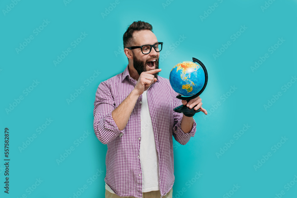 Fototapeta premium Smiling hipster man holding a globe in his hands. The concept of travel, vacation, see the world.