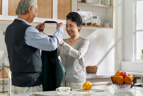 Sticker senior asian man helping wife putting on apron