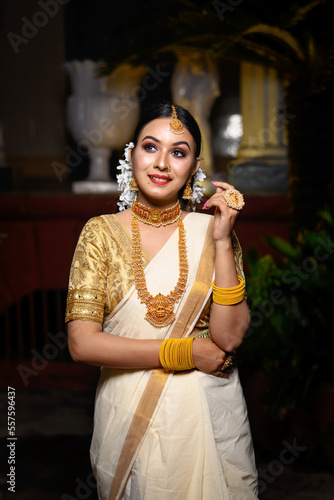 Magnificent young Indian bride in luxurious bridal costume with makeup and heavy jewellery standing in front of a vintage background. Lifestyle and Fashion. Ethnic wedding and fashion.