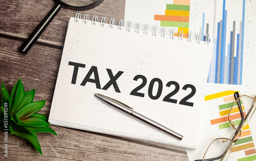Tax 2022, taxation system. Word on white notebook and charts