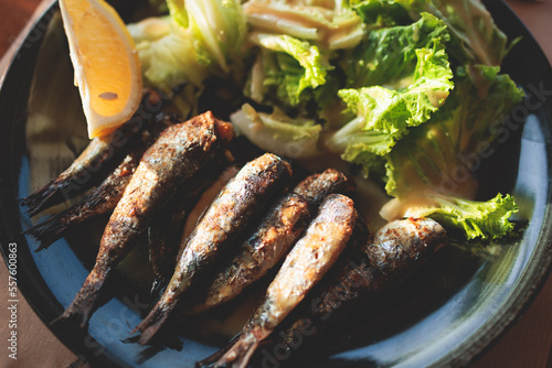 Fototapeta Naklejka Na Ścianę i Meble -  Close-up of traditional greek dish - grilled sardines, roasted sardinas on a plate with potatoes and vegetables, in Corfu island old town, Ionian sea, Greece