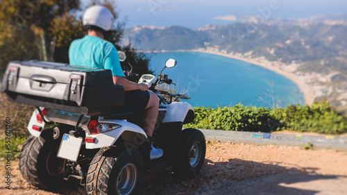Group of riders riding ATV vehicle crossing mountain serpentine road track, process of driving rental vehicle, all terrain quad bike vehicle, during off-road tour, Greece, Ionian sea islands