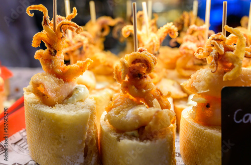 Typical snack of Basque Country, pinchos or pinxtos skewers with small pieces of bread, sea food, baby octopus, cheese, jamon served in bar in San-Sebastian or Bilbao, Spain photo