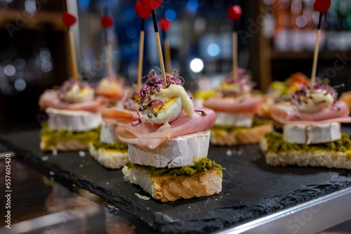Typical snack of Basque Country, pinchos or pinxtos skewers with small pieces of bread, sea food, eggs, cheese, jamon served in bar in San-Sebastian or Bilbao, Spain