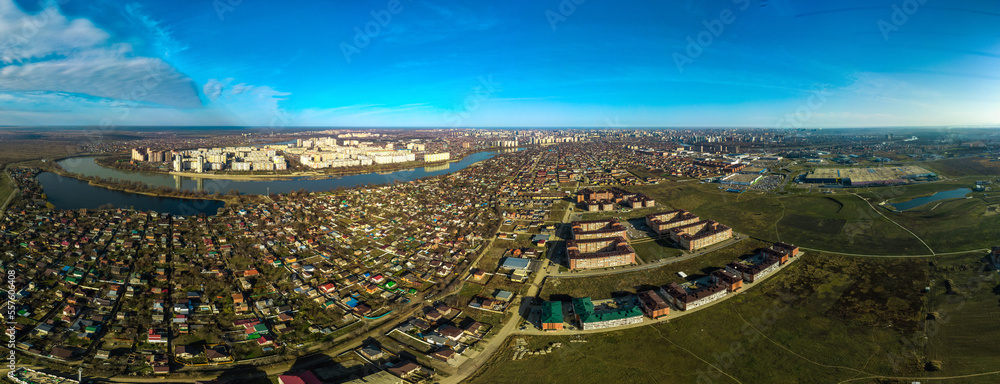 aerial view - low-rise country suburbs of the city of Krasnodar near the bend of the Kuban river with several high-rise buildings and a lake on a sunny winter day